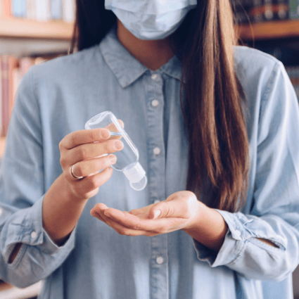 COVID19 in the tech industry - woman applying hand sanitizer while wearing mask